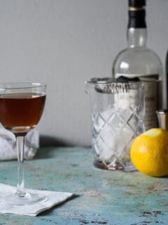 马丁内斯鸡尾酒在一块玻璃用混合玻璃，柠檬，苦味和瓶子