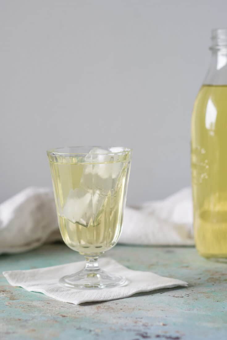 清澈的英国牛奶潘趣酒，玻璃杯里有冰块，背景是一瓶潘趣酒