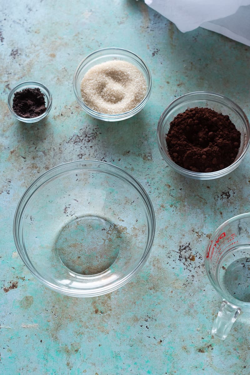 碗浓缩咖啡粉，糖和可可粉与水旁边的水