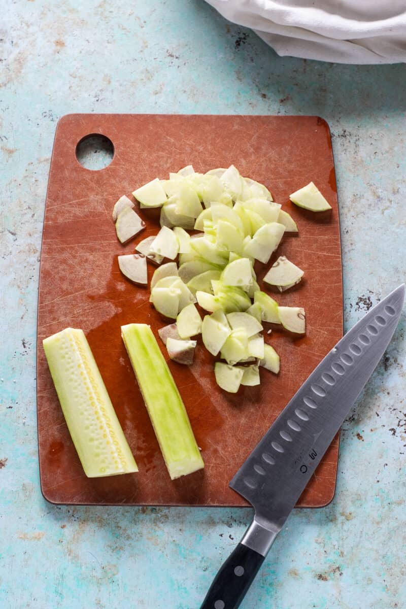 在一个切板的切片黄瓜用厨师的刀子旁边